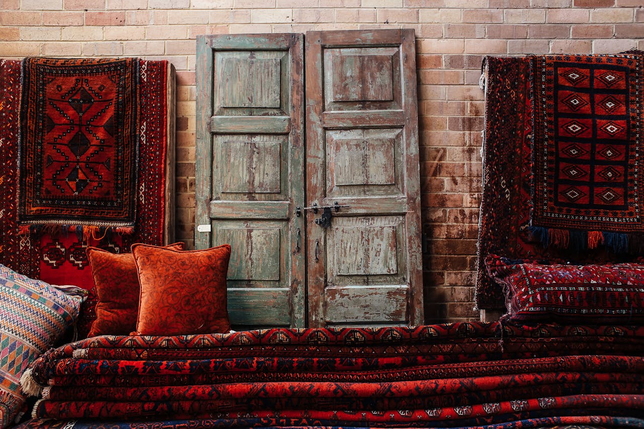 Vintage wooden door surrounded by vibrant, patterned rugs and pillows, creating a warm, rustic ambiance.